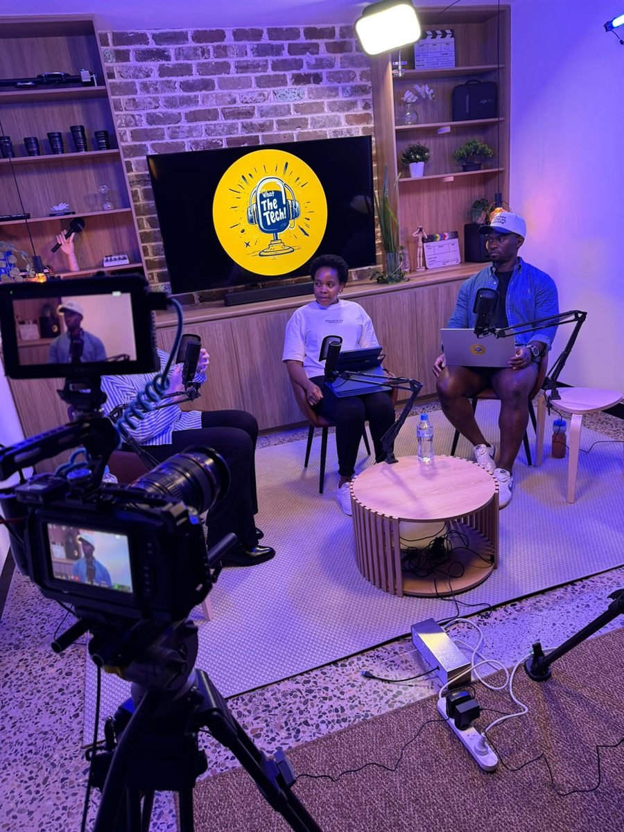 Three podcast guests seated with boom microphones in front of the studio screen