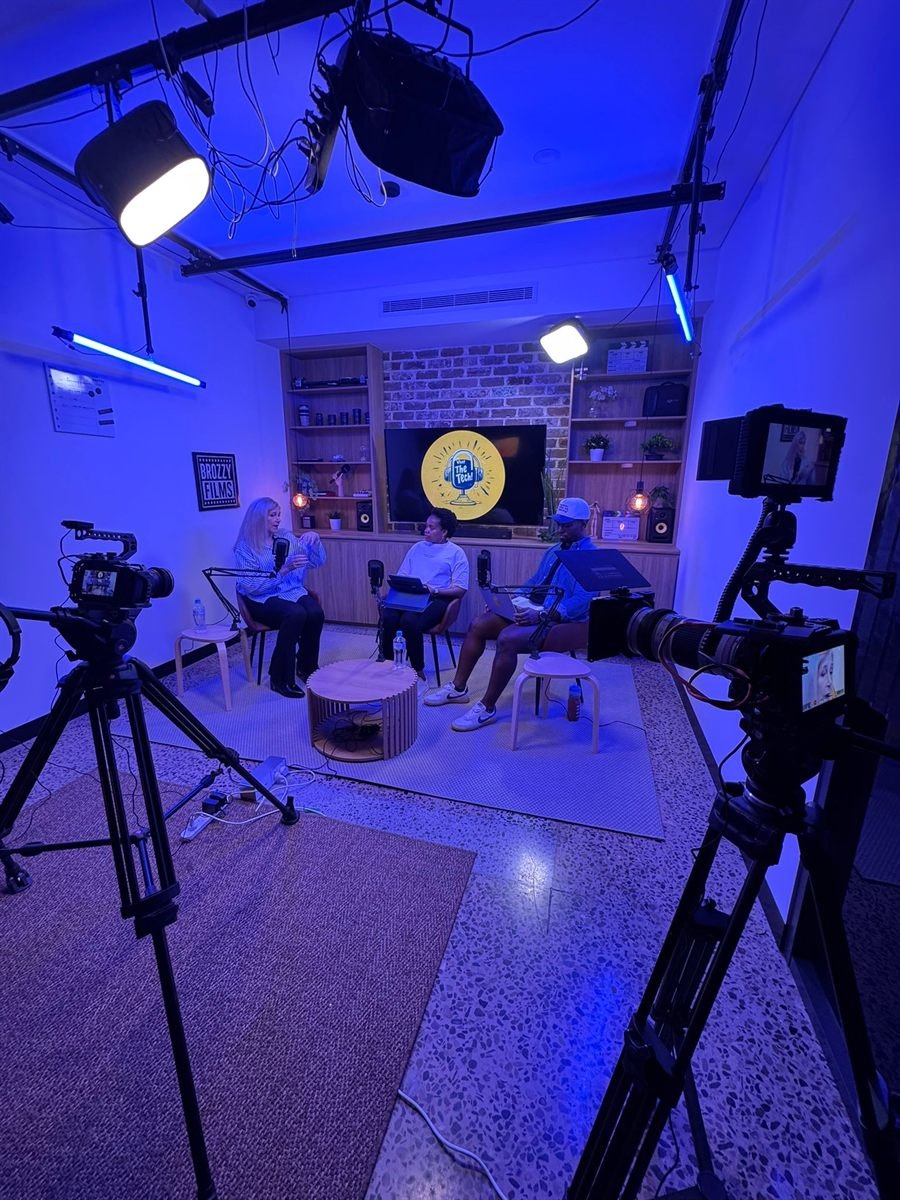 Three cameras on tripods recording a three-guest podcast session on the Dingo Lab set